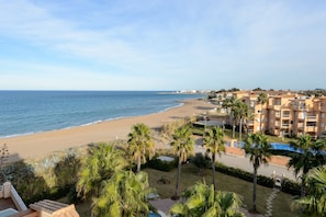 A beachfront hotel with a pool, palm trees, and a view of the sea. - Denia Beachfront apartment by ON Travel (Denia)