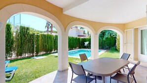 A patio with a pool, surrounded by a well-maintained lawn and tall hedges. - Villa Mar by ON Travel (Oliva)