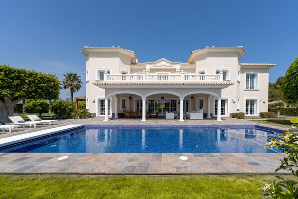 A large two-story house with a swimming pool in front.