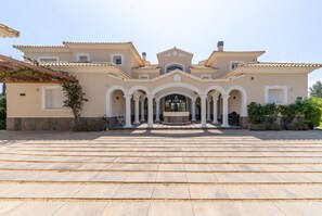 A large, two-story building with a symmetrical facade, multiple arches, and a central fountain.