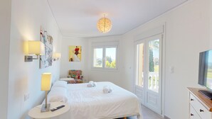Una habitación de hotel con cama, lámparas de noche, televisión, ventana y obras de arte en las paredes.