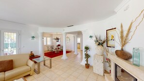 Un soggiorno spazioso con divano, zona pranzo, camino e piante decorative.