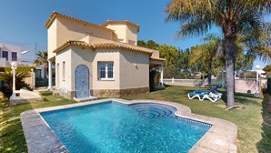 Una casa con piscina, patio empedrado y jardín cercado.