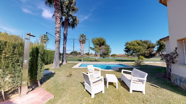 A backyard with a swimming pool, white wicker furniture, and palm trees. - Villa Boreal by ON Travel (Oliva)