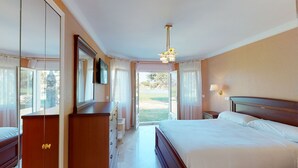 Una habitación de hotel con cama, cómoda, televisor y vistas al exterior.