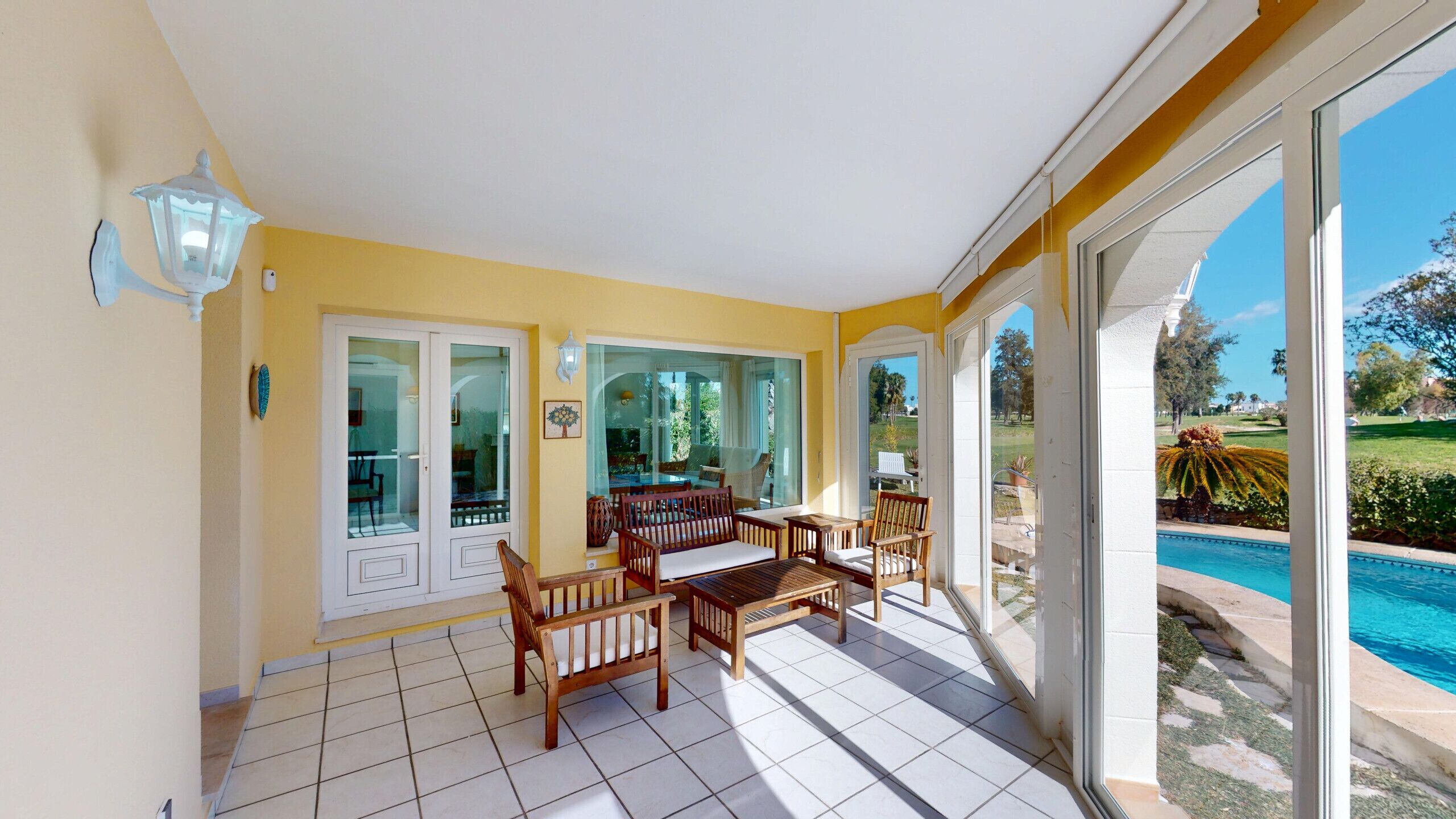 A sunlit patio with a pool view, sliding glass doors, and outdoor furniture.