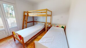 A bunk bed room with a wooden ladder, a small table, and a window.