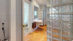 Een badkamer met een wit wastafelmeubel, een spiegel en een glazen douchewand.