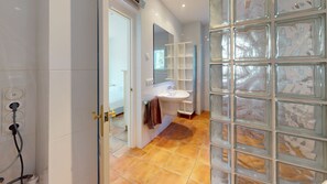 Ein Badezimmer mit einem weißen Waschbecken, einem Spiegel und einer Glasabtrennung.