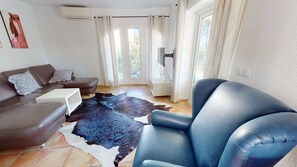 A living room with a brown sofa, a blue armchair, a white coffee table, and a cowhide rug.