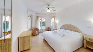 Un dormitorio amplio con una cama grande, muebles de mimbre y un ventilador de techo.