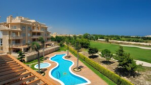 A multi-story hotel with a swimming pool, landscaped gardens, and a view of the sea.