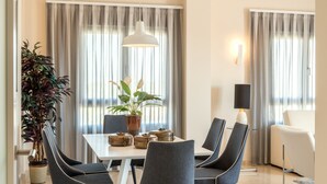Un comedor con una mesa, sillas, una planta en maceta y una lámpara colgante moderna.