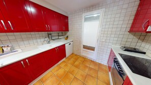 A kitchen with red cabinets, a white sink, and a black stove.