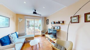 A living room with a sofa, TV, and a balcony with a pool view. - Arena y Brisa by ON Travel (Oliva)