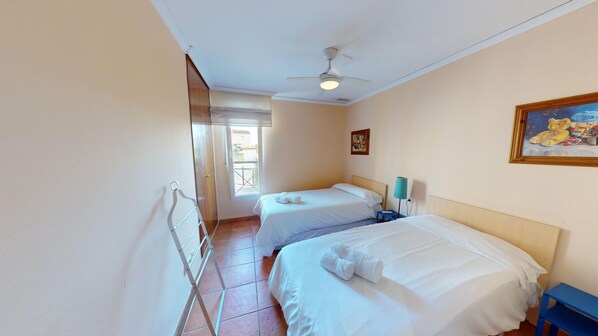 A hotel room with two beds, a ceiling fan, a painting, and a view through a window. - Arena y Brisa by ON Travel (Oliva)