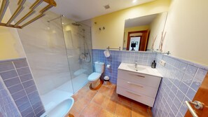 Une salle de bain avec une douche à parois de verre, des toilettes et un lavabo avec un miroir au-dessus.