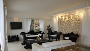 A modern living room with a black sofa, white armchair, and a wooden coffee table. - Luxurious contemporary villa with magnificent sea view Nice, Alpes-Maritimes, France (Nice)