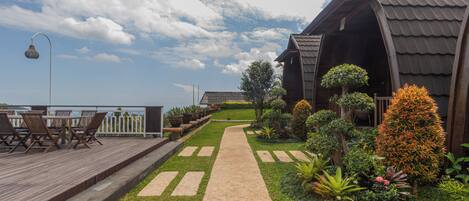 A wooden deck with outdoor furniture, a pathway, and a building with a sloped roof.