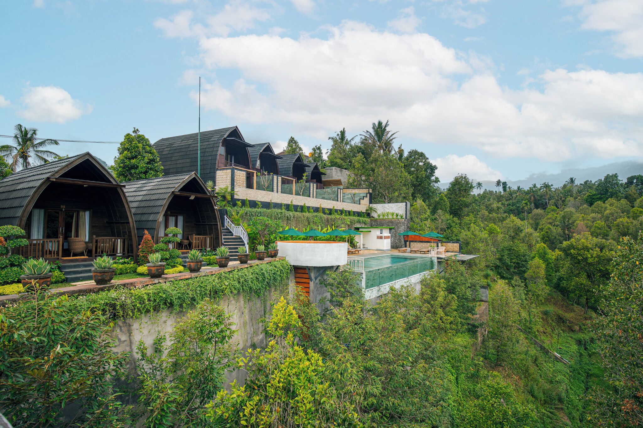 Un resort con varias cabañas, una piscina y abundante vegetación alrededor de la propiedad.