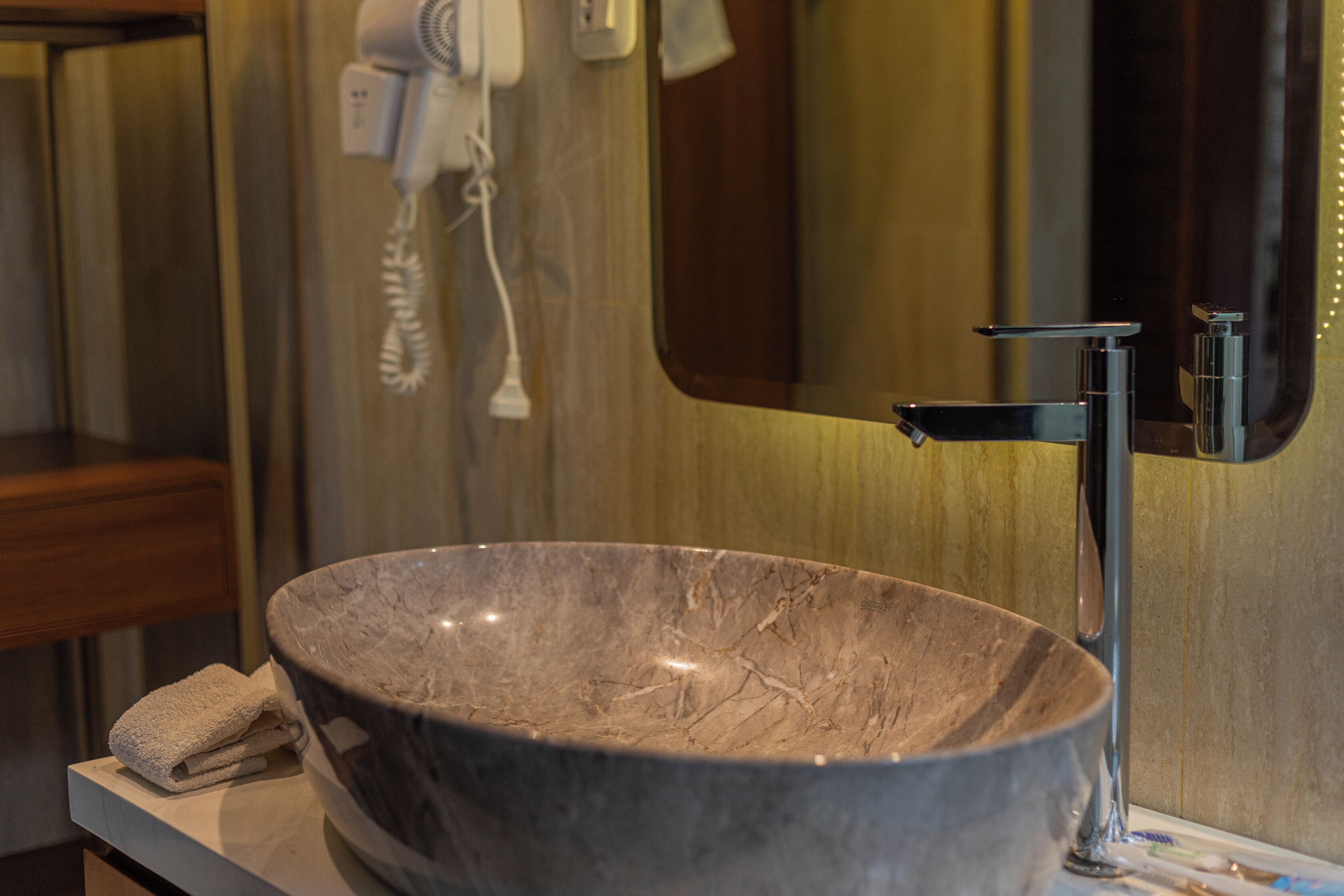 A bathroom with a large marble sink, a mirror, and a towel on the counter.