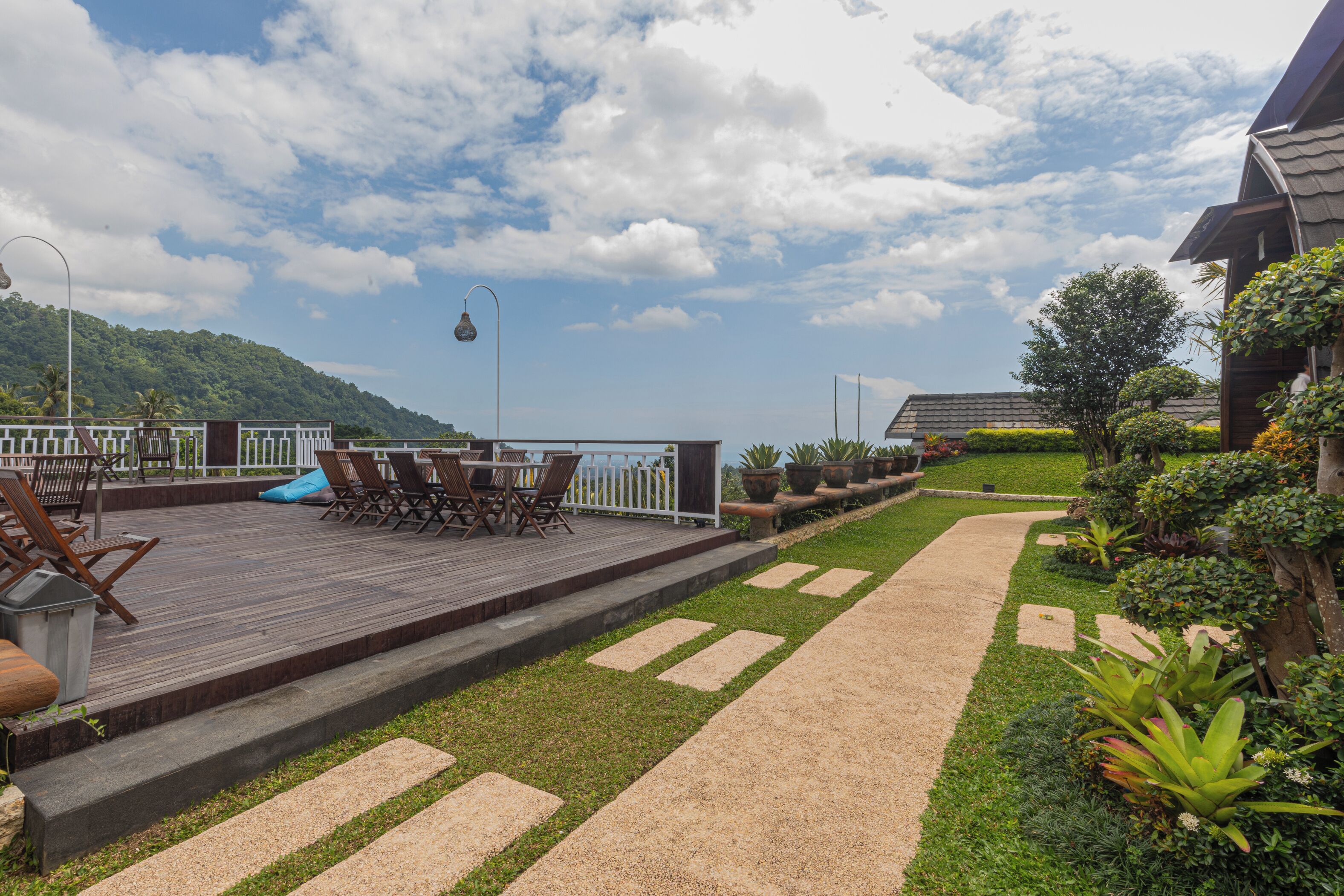 A wooden deck with outdoor furniture, a pathway, and a garden with various plants.