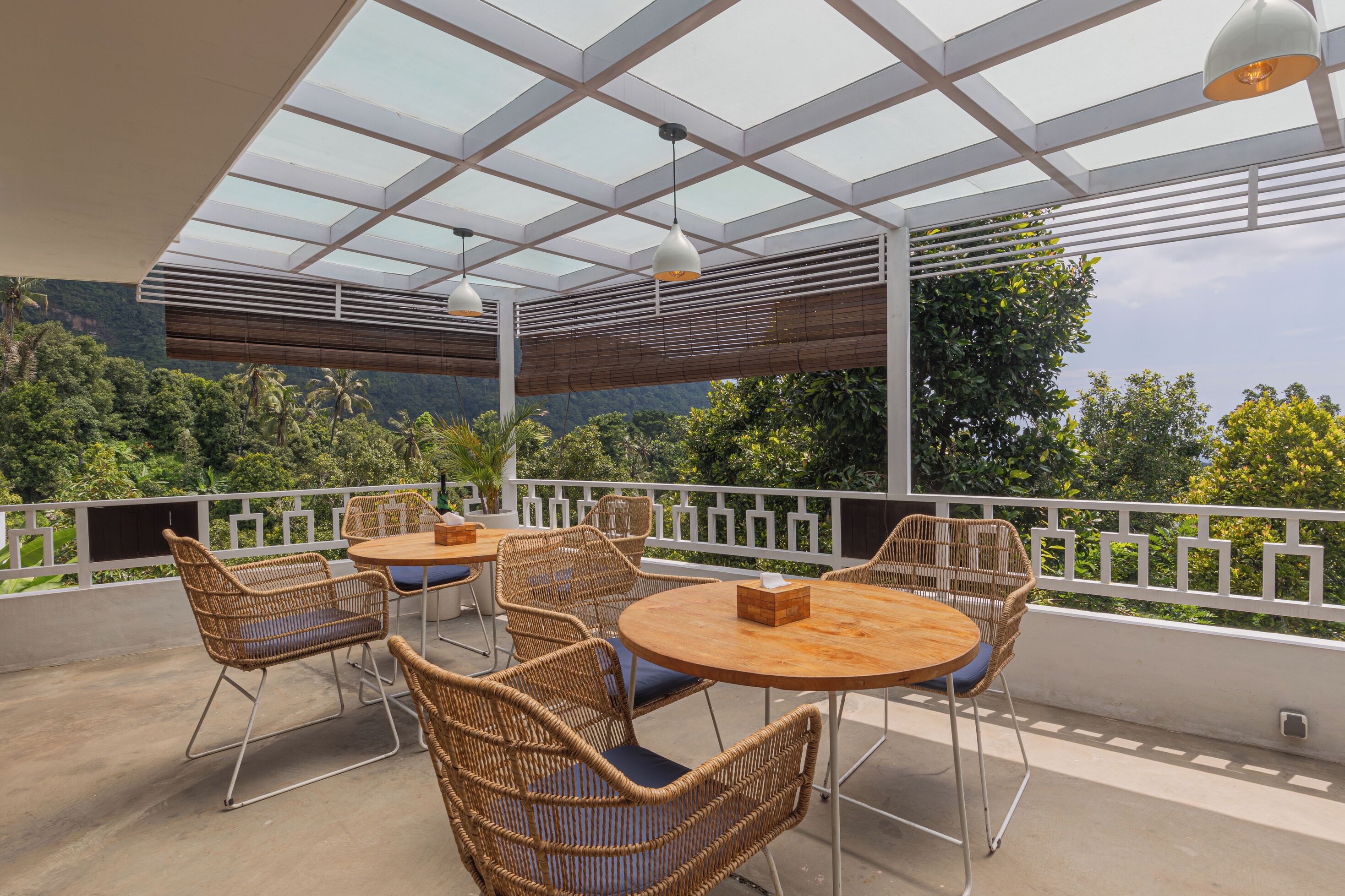 Eine Terrasse im Freien mit Korbmöbeln und einer Glaskuppel, mit Blick auf eine üppige Landschaft.