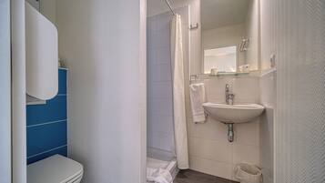 Ein Badezimmer mit Toilette, Dusche, Waschbecken und Spiegel.