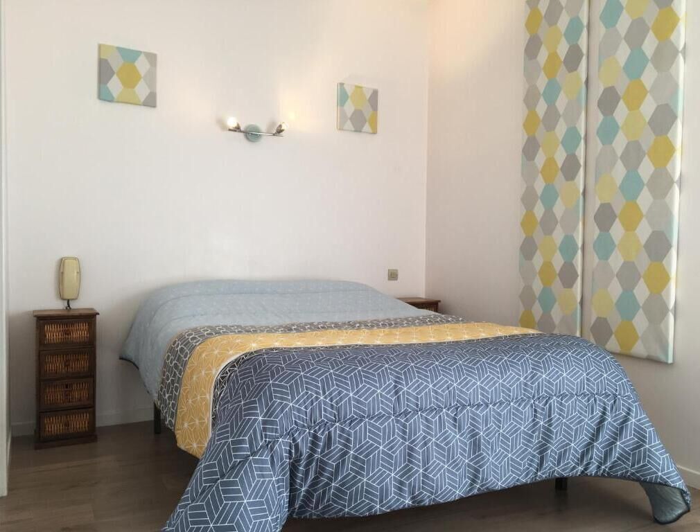 A bedroom with a bed, a nightstand, and a wall-mounted lamp.