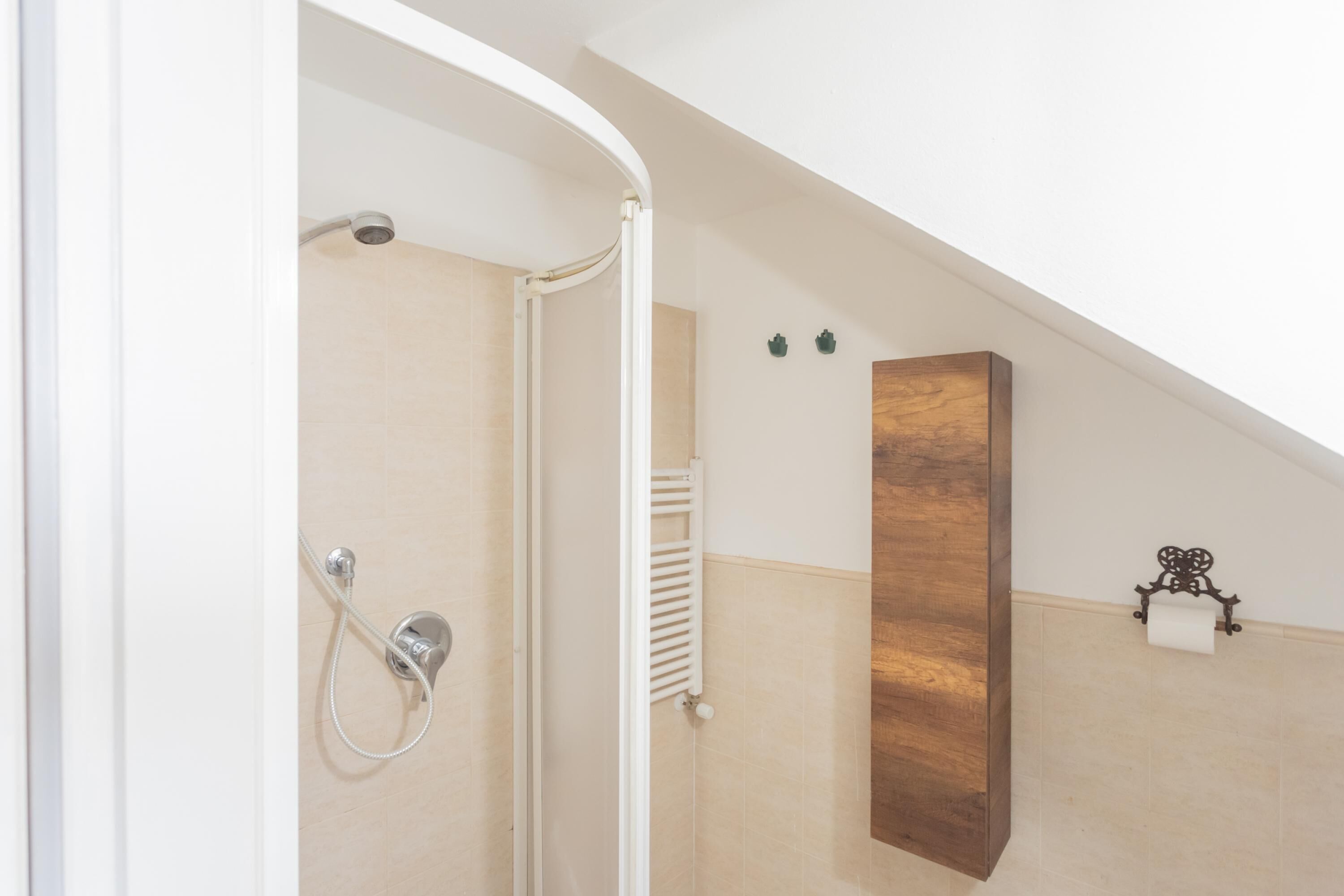 Un baño con ducha, un panel de madera y un perchero.