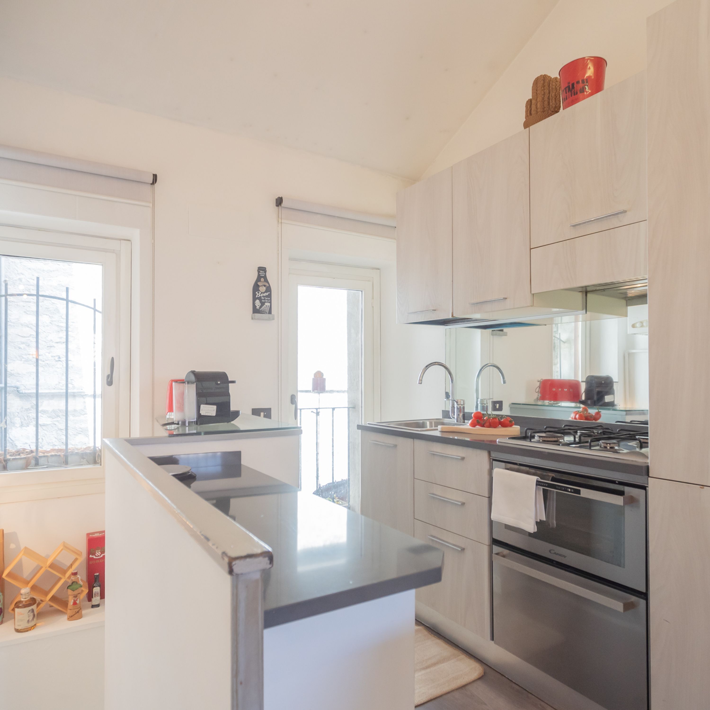 A modern kitchen with a central island, stainless steel appliances, and light-colored cabinetry.