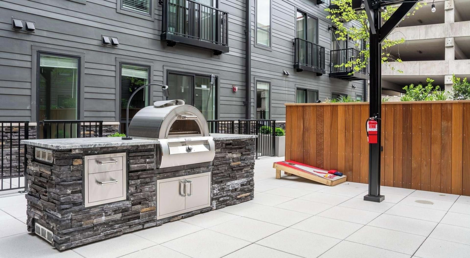 An outdoor kitchen with a stone facade, a built-in grill, and a wooden bench.