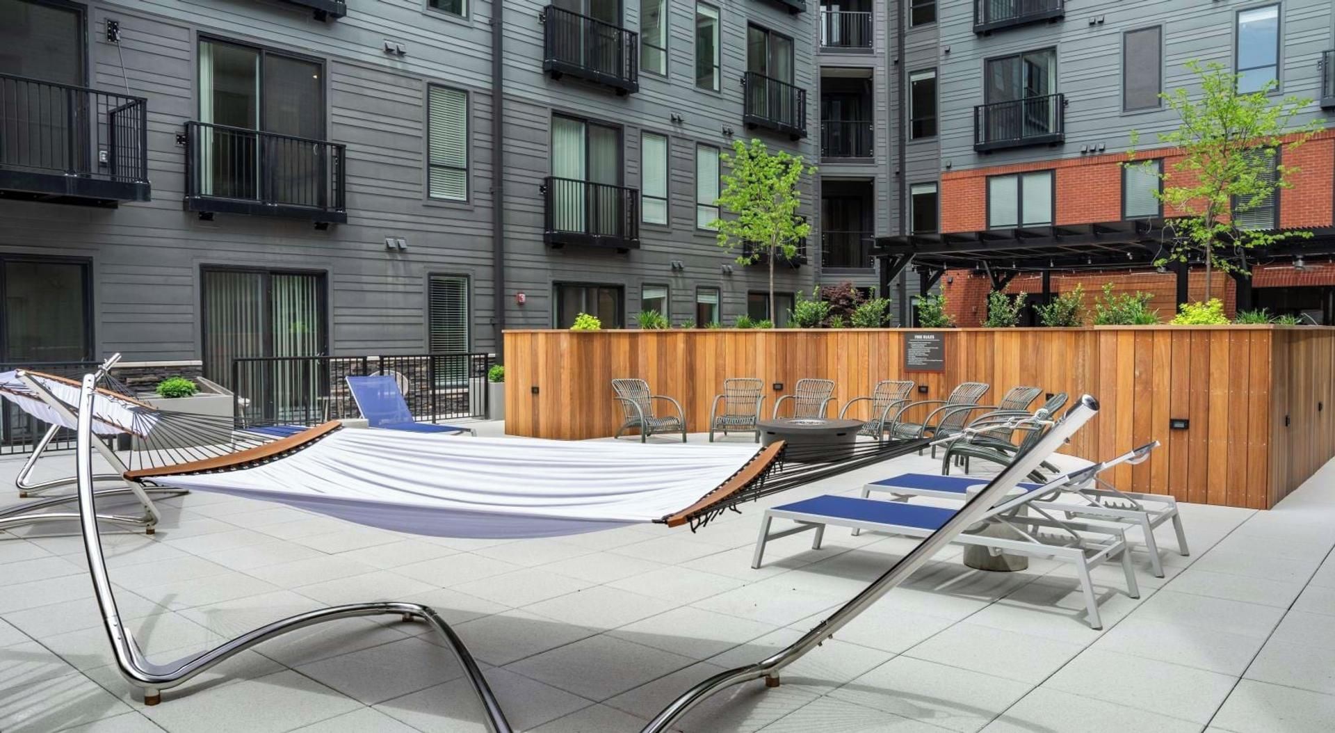 Une terrasse sur le toit équipée d’un hamac, de chaises longues et d’une plateforme en bois avec des sièges.