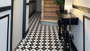 A hallway with a black and white patterned floor, a wooden staircase, and a mirror on the wall. - Maison du Roi (Liege)