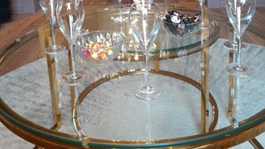 A dining area with a round glass table surrounded by chairs, a chandelier, and a floral arrangement on the table. - Maison du Roi (Liege)