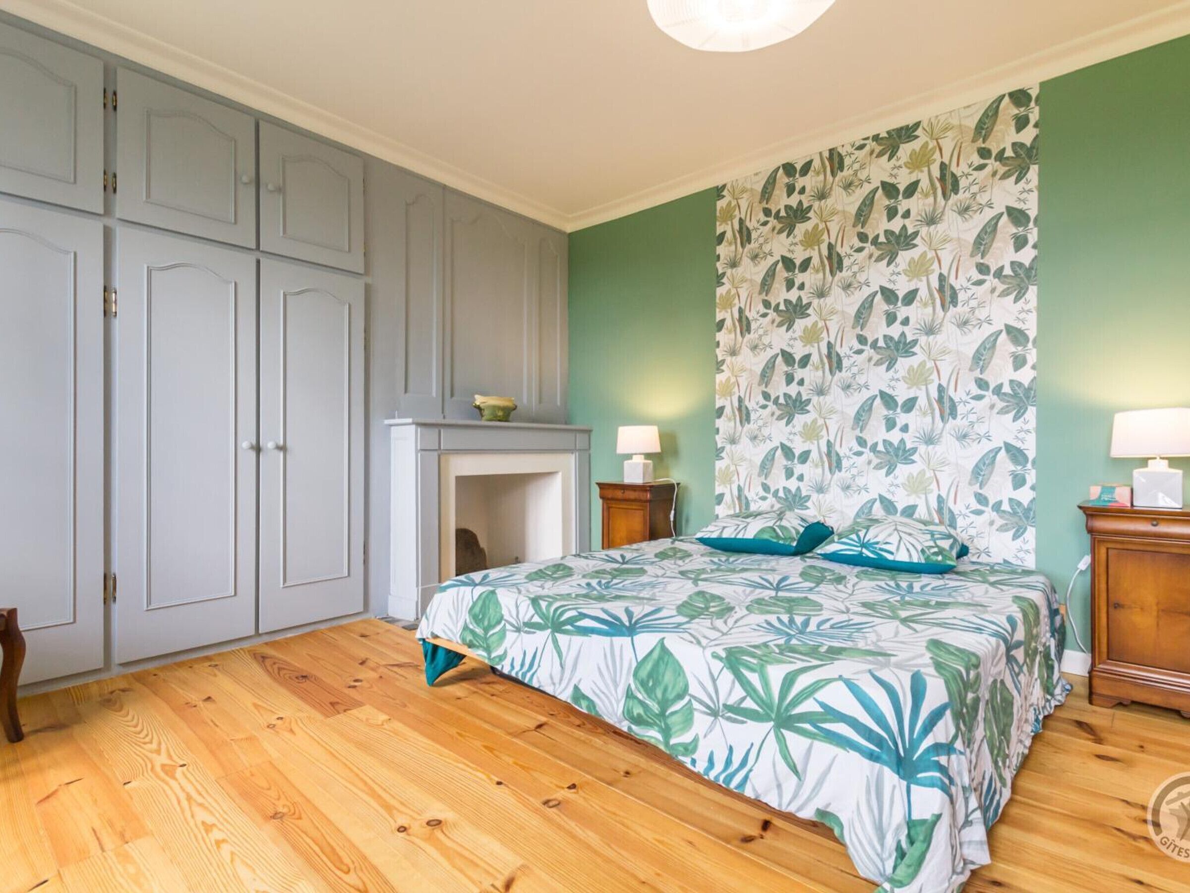 Une chambre à coucher avec un lit, une table de chevet, une commode et une cheminée.