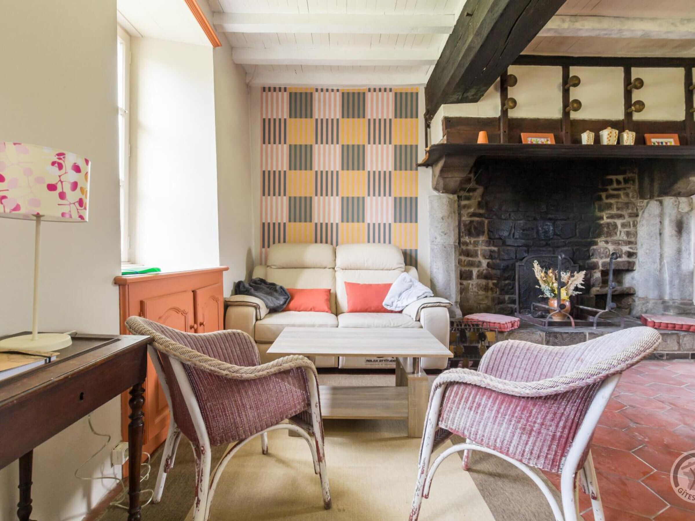 Ein gemütliches Wohnzimmer mit Kamin, Wand mit Muster und Korbstühlen.