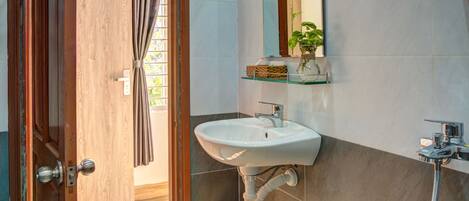 Ein modernes Badezimmer mit Holztür, Waschbecken, Spiegel und Dusche.