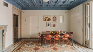 A dining area with a patterned floor, a table with chairs, and a ceiling with blue painted beams. - Piulet Hostel (Barcelona)