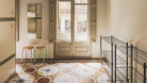 A hallway with ornate ceiling details, a patterned floor, and a door with glass panels. - Piulet Hostel (Barcelona)