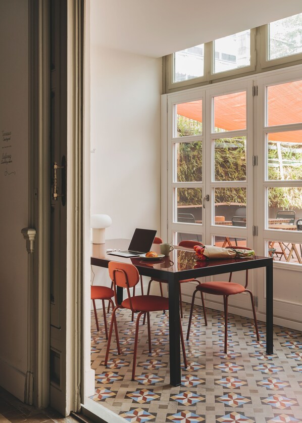 A dining area with a table, chairs, and a laptop. - Piulet Hostel (Barcelona)