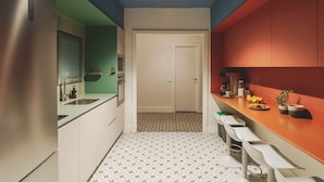 A modern kitchen with a central island, white cabinets, and a patterned floor. - Piulet Hostel (Barcelona)
