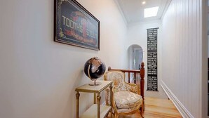 A hallway with a globe on a small table, a framed poster on the wall, and a list of names on a vertical banner.
