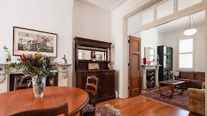 A dining area with a wooden table and chairs, a fireplace, and a mirror above it.