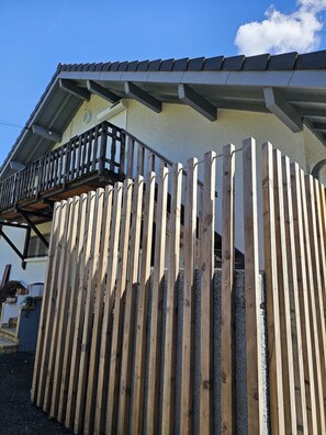 A wooden fence in front of a building with a balcony. - Appartement Indépendant à 10 Minutes D'annecy, Juste à Côté des Chemins de Rando (Poisy)