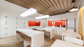 A modern kitchen with white cabinets, wooden beams, and bright overhead lighting. - Porta da Arrábida Suites (Palmela)