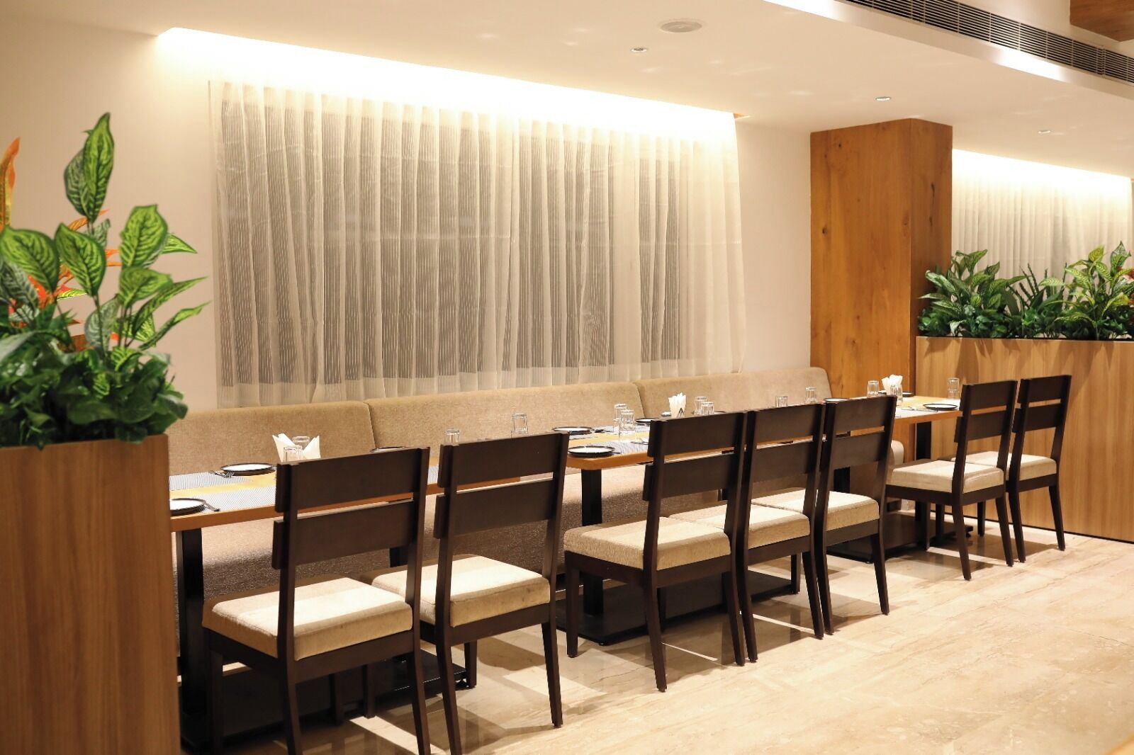 A dining area with a long table, multiple chairs, and a sofa.