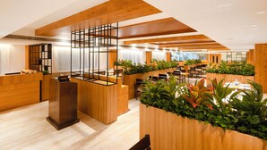A modern hotel lobby with wooden reception desks, seating areas, and indoor plants. - Icon Grand Hotel by Bhagini (Bengaluru)