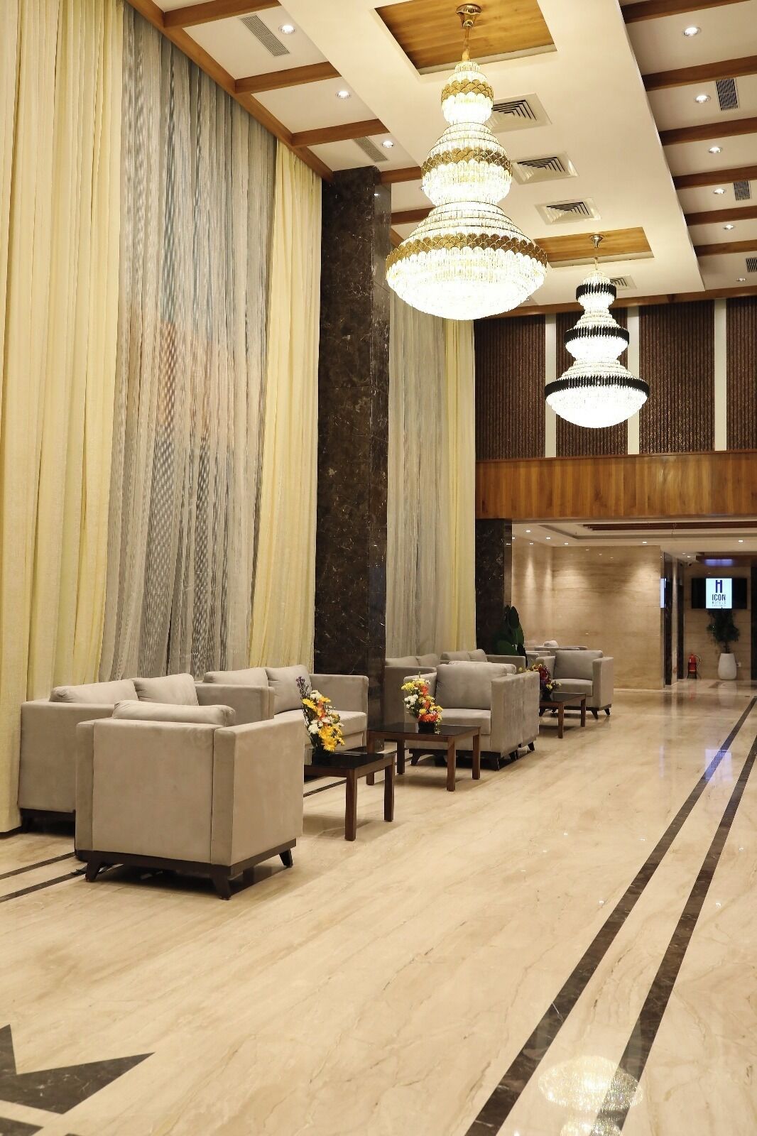 A spacious lobby with a marble floor, multiple sofas, and a large chandelier.