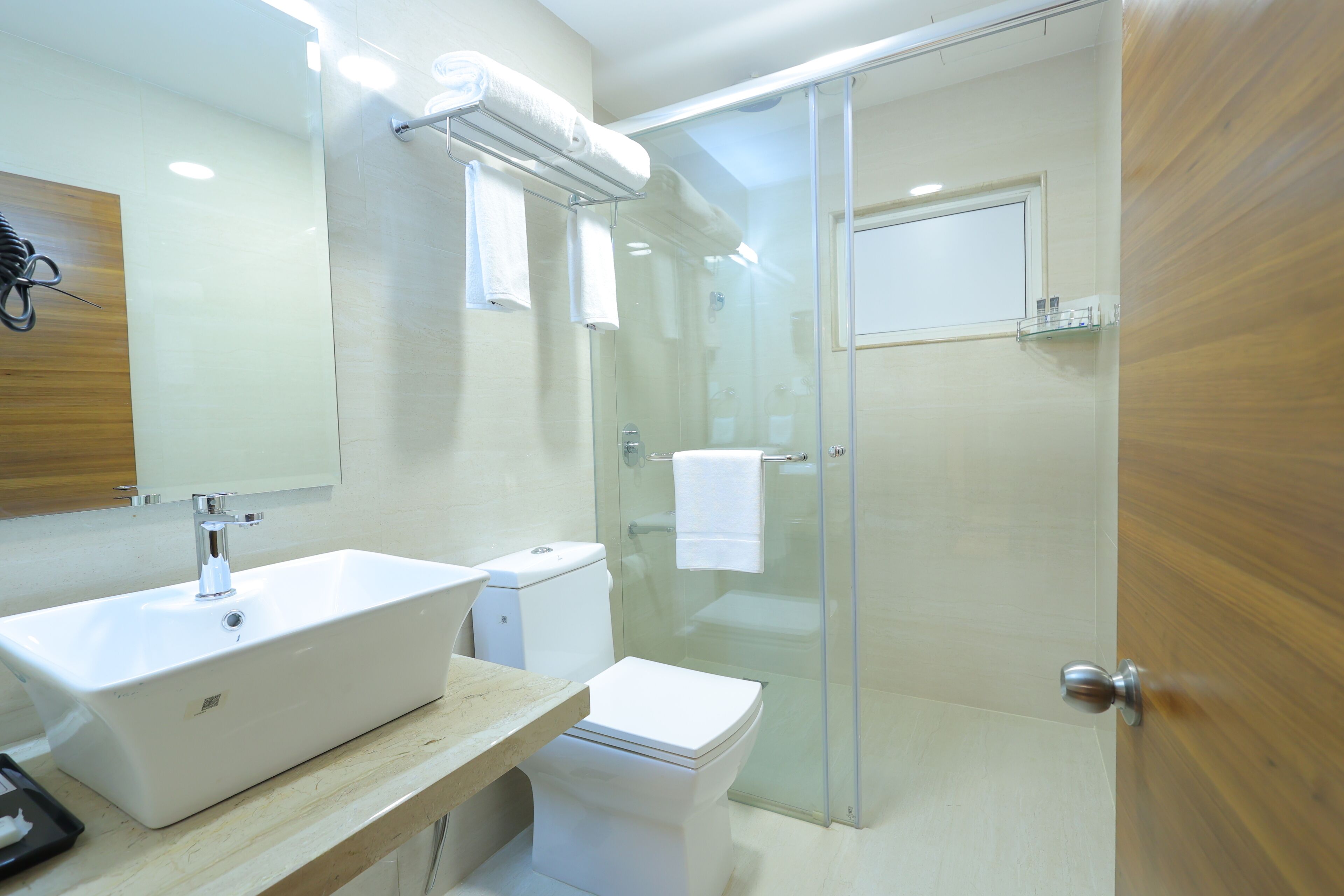 Un baño moderno con un lavabo blanco grande, un inodoro y una zona de ducha con mampara de vidrio.